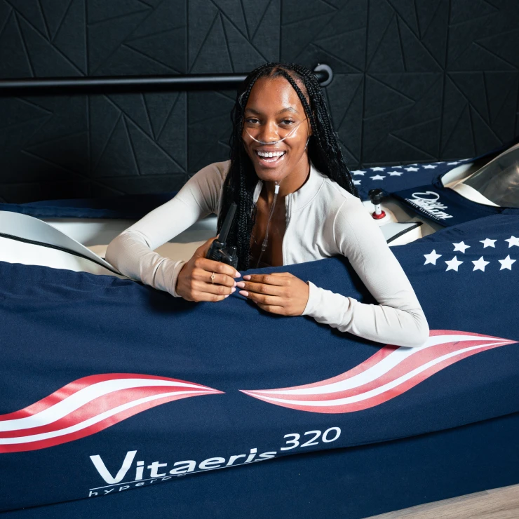 Smiling woman sitting inside a Mild Hyperbaric Oxygen Therapy chamber